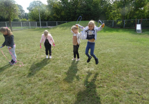 dziewczynki skaczą na skakance na trawie